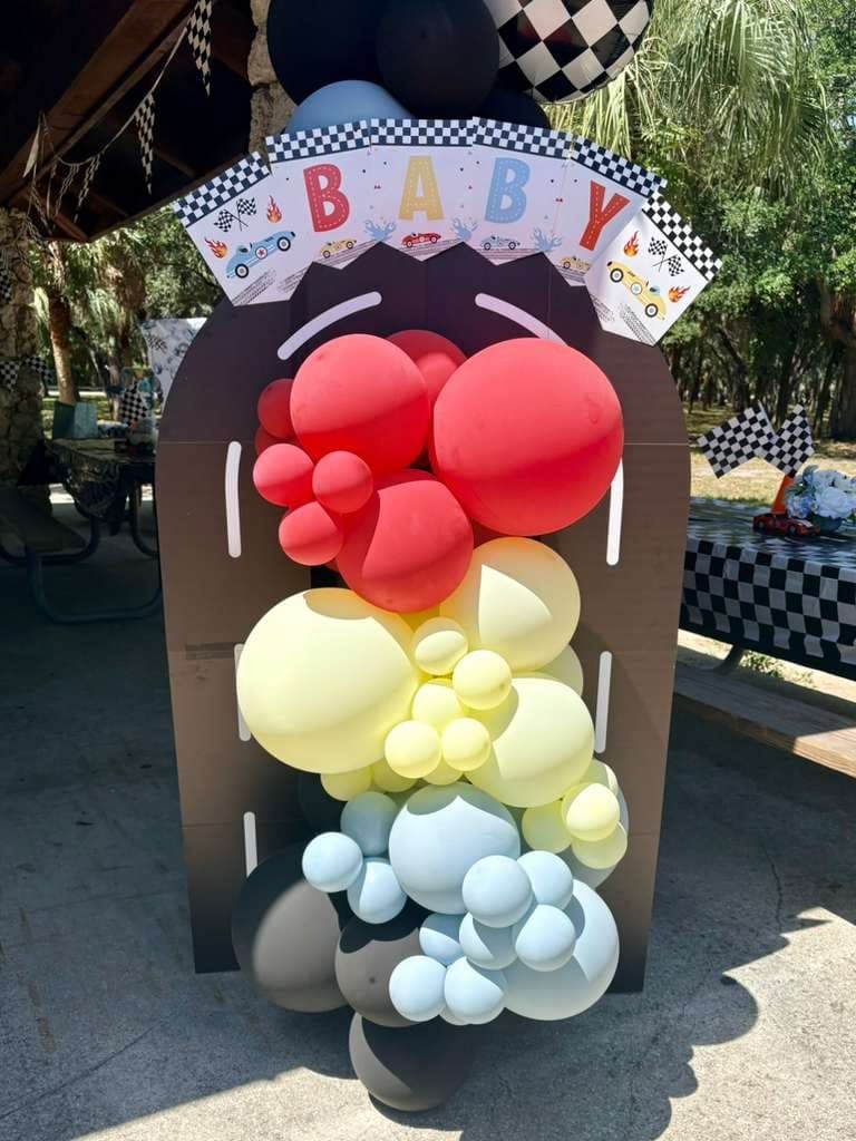 Race car shaped balloon garland with checkered flags and a 'BABY' banner