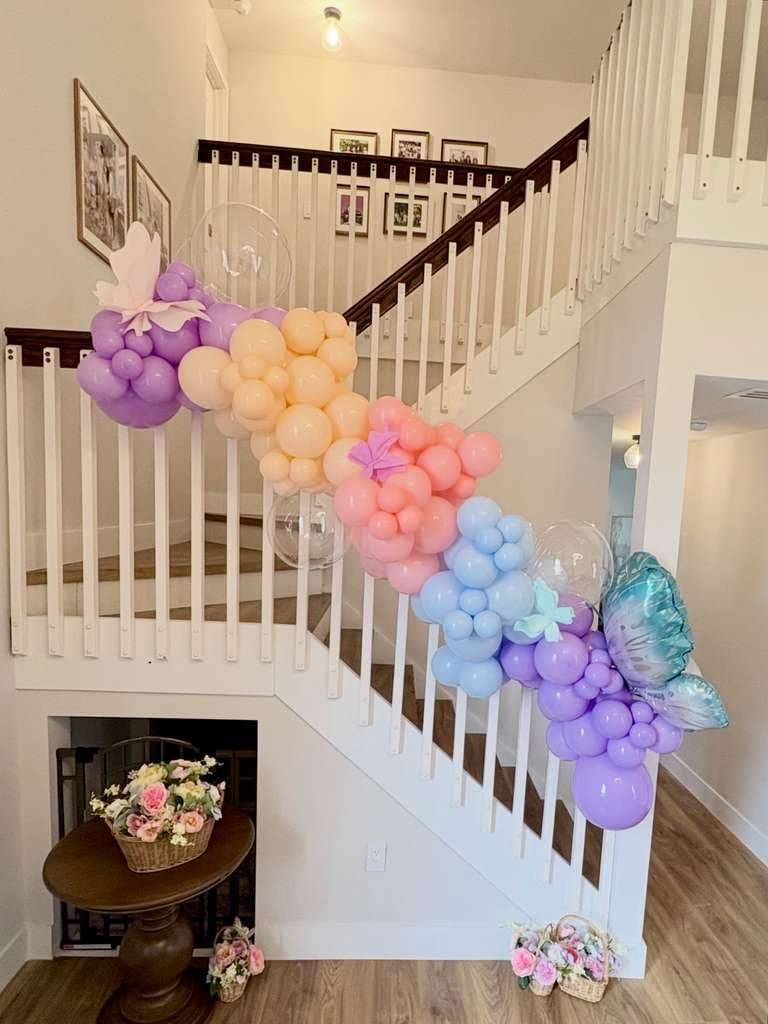 Pastel butterfly balloon garland flowing down a staircase railing