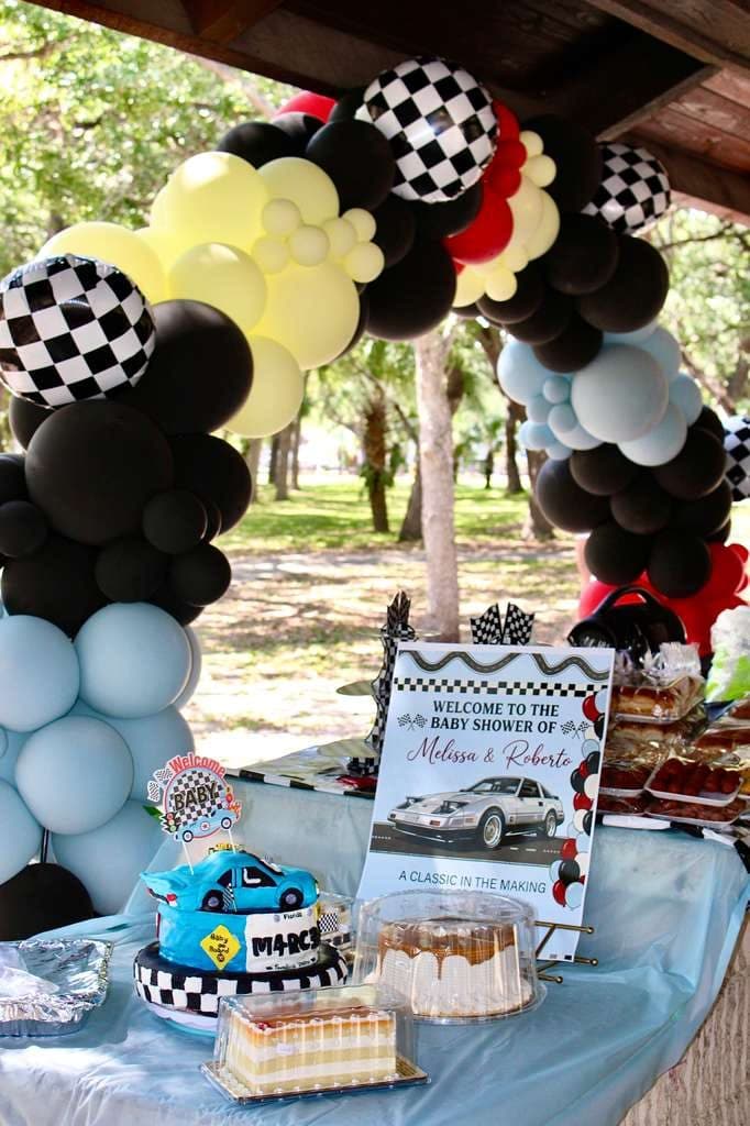 Checkered flag balloon arch over a dessert table with race car themed cake